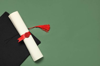 Mezuniyet şapkası ve yeşil arka plan diploması.