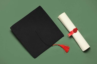 Mezuniyet şapkası ve yeşil arka plan diploması.