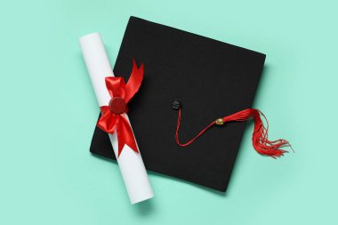 Mezuniyet şapkası ve turkuaz arka plan diploması.
