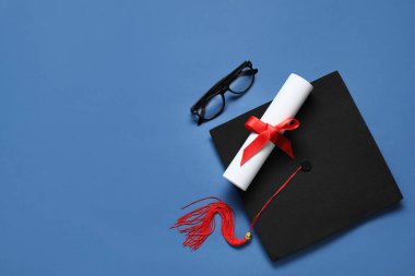 Mezuniyet şapkası, gözlükler ve mavi arka plan diploması.