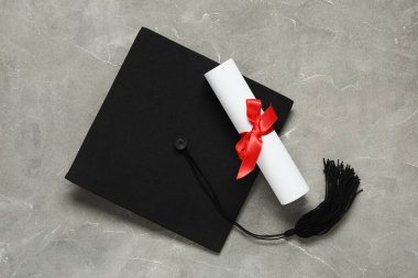 Mezuniyet şapkası ve gri arka plan diploması, üst görünüm