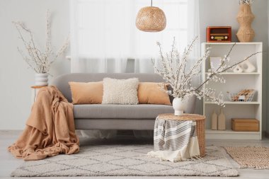 Aydınlık oturma odasının içinde çiçek açan vazolar.