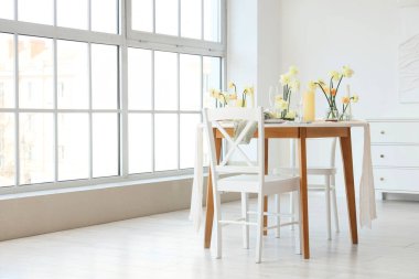 Narcissus çiçekleri ve mumlarla aydınlık odada güzel bir masa.