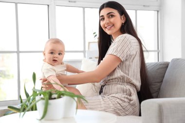 Mutlu anne ve küçük bebeği evdeki kanepede oturuyor.