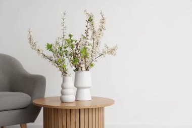 Aydınlık oturma odasındaki masada çiçek açan vazolar.