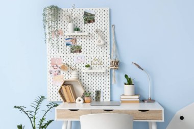 Ofiste mavi duvarda bitkiler ve tahta olan modern işyeri