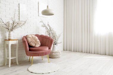 Oturma odasının içinde pembe koltuklar ve vazolarda çiçek açan dallar.
