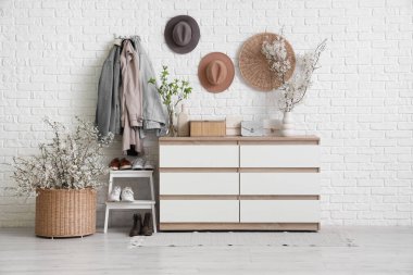 Sallanan giysiler, merdiven ve komodindeki vazolarda açan güzel dallarla oturma odasının içinde.