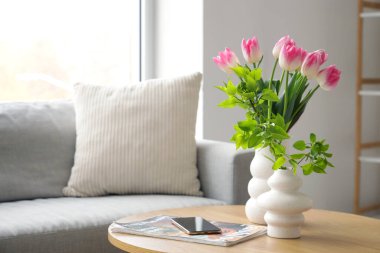 Laleli vazolar, cep telefonu ve dergi oturma odasındaki masada.