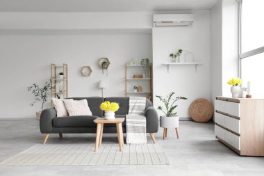 Siyah kanepe, masa ve bitkilerle aydınlık oturma odasının içinde.