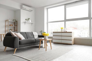 Siyah kanepe, masa ve bitkilerle aydınlık oturma odasının içinde.