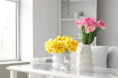 Bahar çiçekli vazolar ve oturma odasındaki masada heykelcikler.