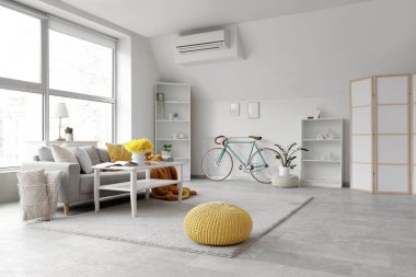 Gri kanepe, masa ve bisikletle aydınlık oturma odasının içinde.