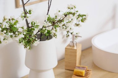 Banyodaki masanın üzerinde çiçek açan dalları olan vazo, yakın plan.