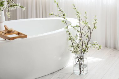 Odada küvetin yanında çiçek açan bir vazo.