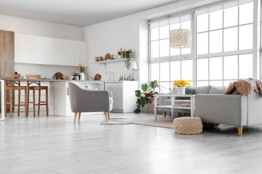 Mutfağın içinde tezgahlar, kanepeler ve bahar çiçekleri var.