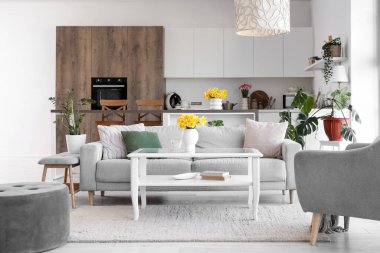 Mutfağın içinde tezgah, kanepe ve bahar çiçekleri var.