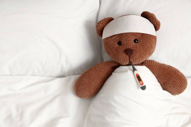 Yatakta termometresi olan oyuncak ayı, üst görüş. Soğuk kavram