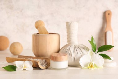 Spa aksesuarları, kozmetik ürünleri ve açık ahşap masa üzerinde orkide çiçekleri olan kompozisyon