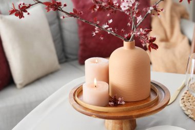 Yanan mumlar ve çiçek açan ağaç dallarıyla şık masa ayarı, yakın plan.