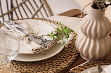 Katlanmış peçete, çatal bıçak takımı ve çiçek açan ağaç dallı şık masa ayarı, yakın plan.