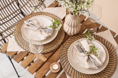 Tabakları, yanan mumları ve çiçek açan ağaç dalları olan zarif bir masa. Yakın plan.