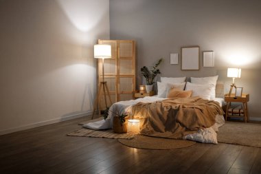 Akşamları çerçeveli, çiçekli ve parlayan lambalı rahat bir yatak odası.