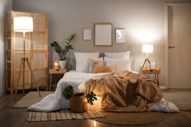 Akşamları çerçeveli, çiçekli ve parlayan lambalı rahat bir yatak odası.