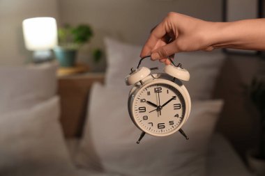 Geceleri yatak odasında çalar saati olan bir kadın, yakın plan.