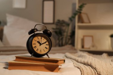 Geceleri yatağında kitaplar olan çalar saat, yakın plan.