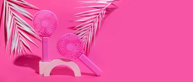 Taşınabilir elektrikli vantilatörlü sıva podyumu ve pembe arka planda metin için alanı olan palmiye yaprakları