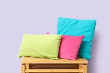 Ahşap çekmecede, leylak duvarın yanında şık yastıklar.