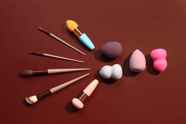 Kırmızı arkaplanda makyaj süngerleri ve fırçalar