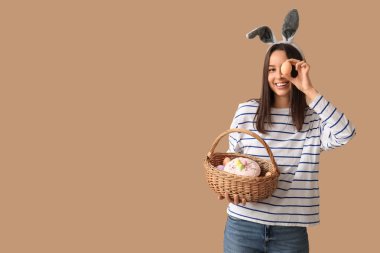 Tavşan kulaklı güzel bir bayan ve bej arka planda Paskalya sepeti.