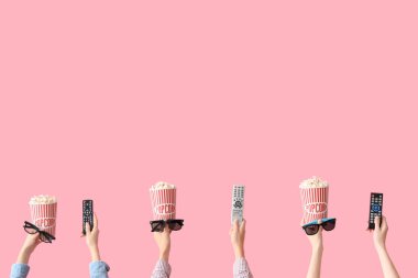 Kovalarca patlamış mısır, 3 boyutlu gözlük ve pembe arka planda televizyon kumandalı eller.