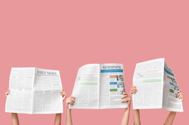 Pembe arka planda gazeteleri olan kadınlar
