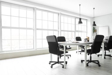 Toplantı için masa hazırlanmış modern ofisin içi.