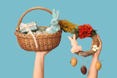 Paskalya bayramı çelengi ve mavi arka planda sepeti olan kadın eller.