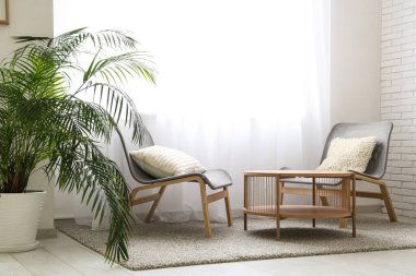 Sandalyeleri ve ışık perdeleri olan şık bir oturma odası.