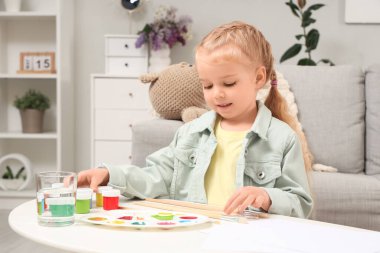 Evdeki tabloları ve fırçaları olan sevimli küçük bir kız.