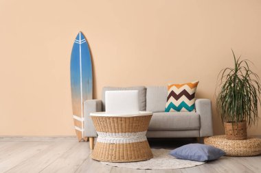 Sörf tahtası, rahat kanepe ve oturma odasında dizüstü bilgisayarı olan bir sehpa.