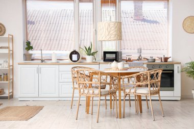 Yemek masası, raf ünitesi, sandalye ve lamba olan şık bir mutfak.