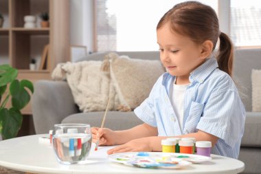 Evinde bir bardak su tablosu olan sevimli küçük bir kız.