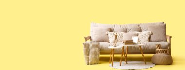 Rahat kanepe, puf ve sehpa sarı arka planda mesaj için yer var.