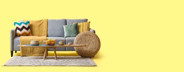 Rahat gri kanepe, masa ve hasır puf sarı arka planda metin için boşluk