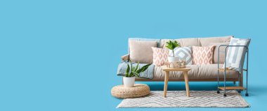 Rahat kanepe, ev bitkileri, açık mavi arka planda masa ve halı.