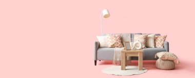 Rahat kanepe, masa, puf ve halı pembe arka planda, mesaj için yer var.