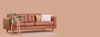 Modern kanepe ve bitki bej arka plana karşı ayakta duruyor ve metin için yer var.