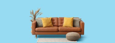 Yastıklı rahat bir kanepe, açık mavi arka planda puf ve halı.