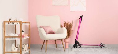 Oturma odasının içinde elektrikli scooter, koltuk ve raf ünitesi var.